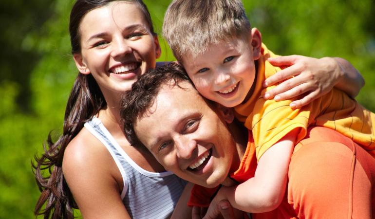 Famiglia felice abbracciata all'aperto, sorrisi pieni di gioia e amore.